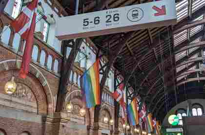 copenhagen central station during pride, rainbow flags among danish flags