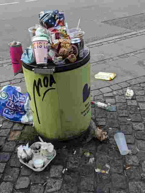 picture of a copenhagen overflowing trash can; coffee cup sticking out which says 'love is love'