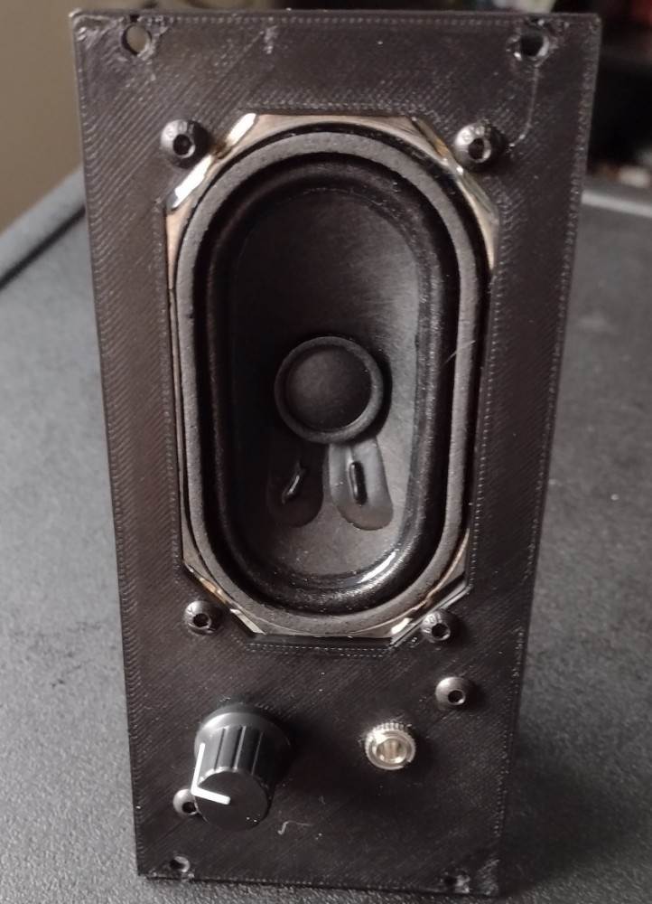 A picture of the front of the module. It has a black rectangular panel, with a speaker taking up the top two thirds of the panel, while a knob and a 3.5mm jack sit below. There are no labels on this module.