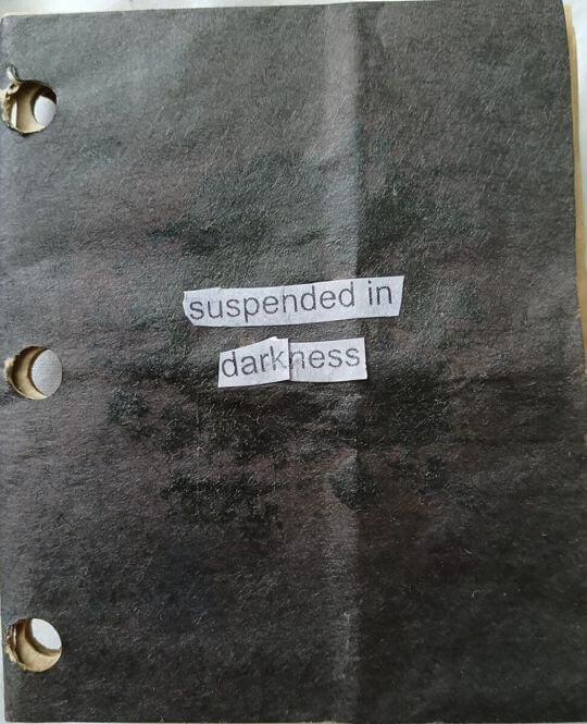 paper that is completely black, except for the words 'suspended in darkness' in the center of the page.